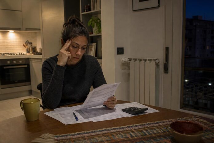 Persona che esamina documenti di bollette in una cucina italiana al tramonto
